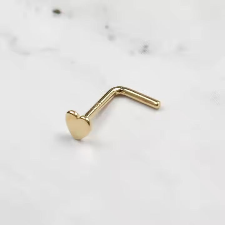 Een minuscuul stalen hartje versiert de neus, een minimalistisch symbool van tijdloze romantiek