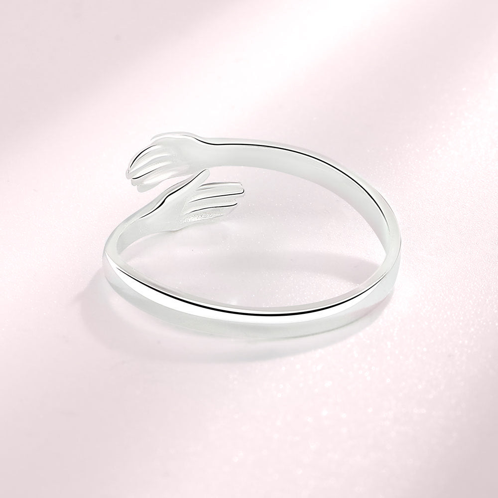Een sterling zilveren ring met handen die zachtjes rond de vinger wikkelen, en genegenheid en tederheid uitdrukken