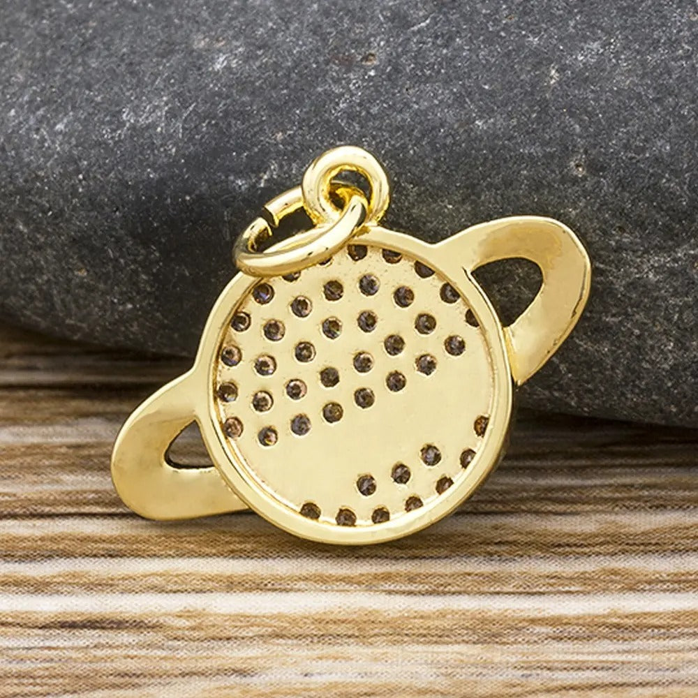 Een gouden planeet-bedeltje, met een delicate ring die een glinsterende bol omcirkelt, en het heelal in miniatuur elegantie vastlegt