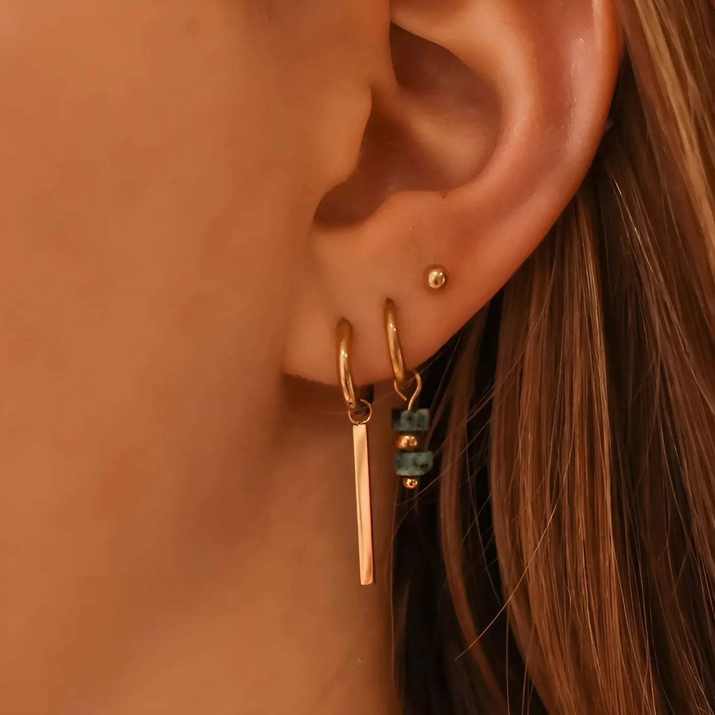 Elegant trio gouden oorbellen: hoops met hangende staafjes, blauw-bead hoops en minimalistische studs, perfect voor elke gelegenheid.