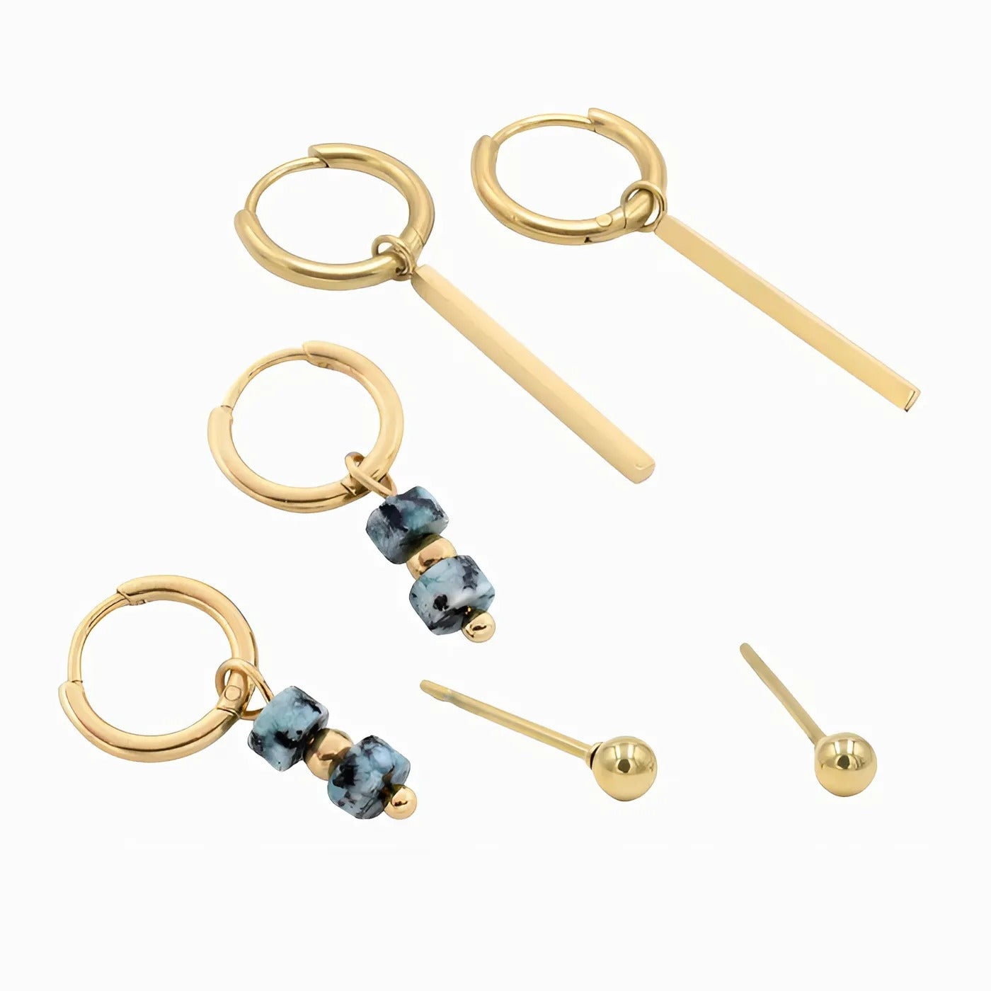 Een set van drie oorbellen: gouden hoops met slanke staafjes, hoops met blauwe kralen en ingetogen studs, veelzijdig en chic.