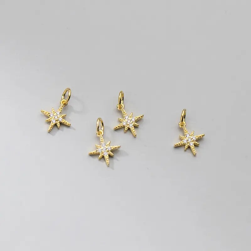 Een verfijnd ochtendster-bedeltje in goud, versierd met zirconia-steentjes, weerspiegelt de serene gloed van de dageraad