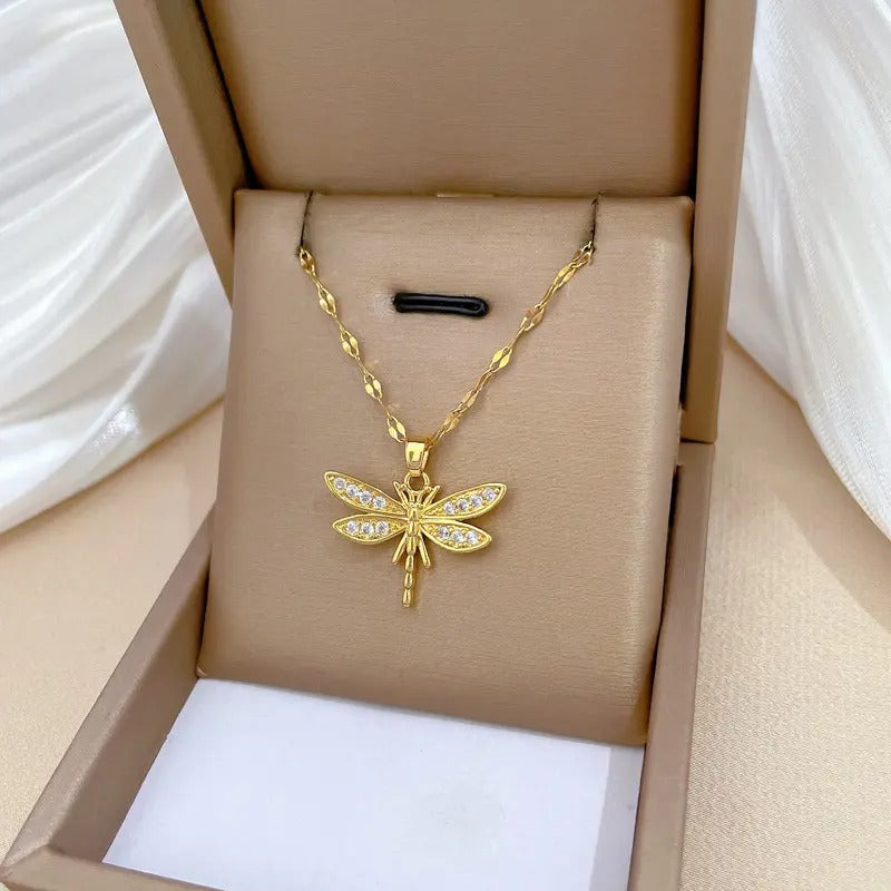 Een gouden libelle-bedeltje, waarvan de vleugels glinsteren met zirconia en de delicate dans van zonlicht op water oproepen