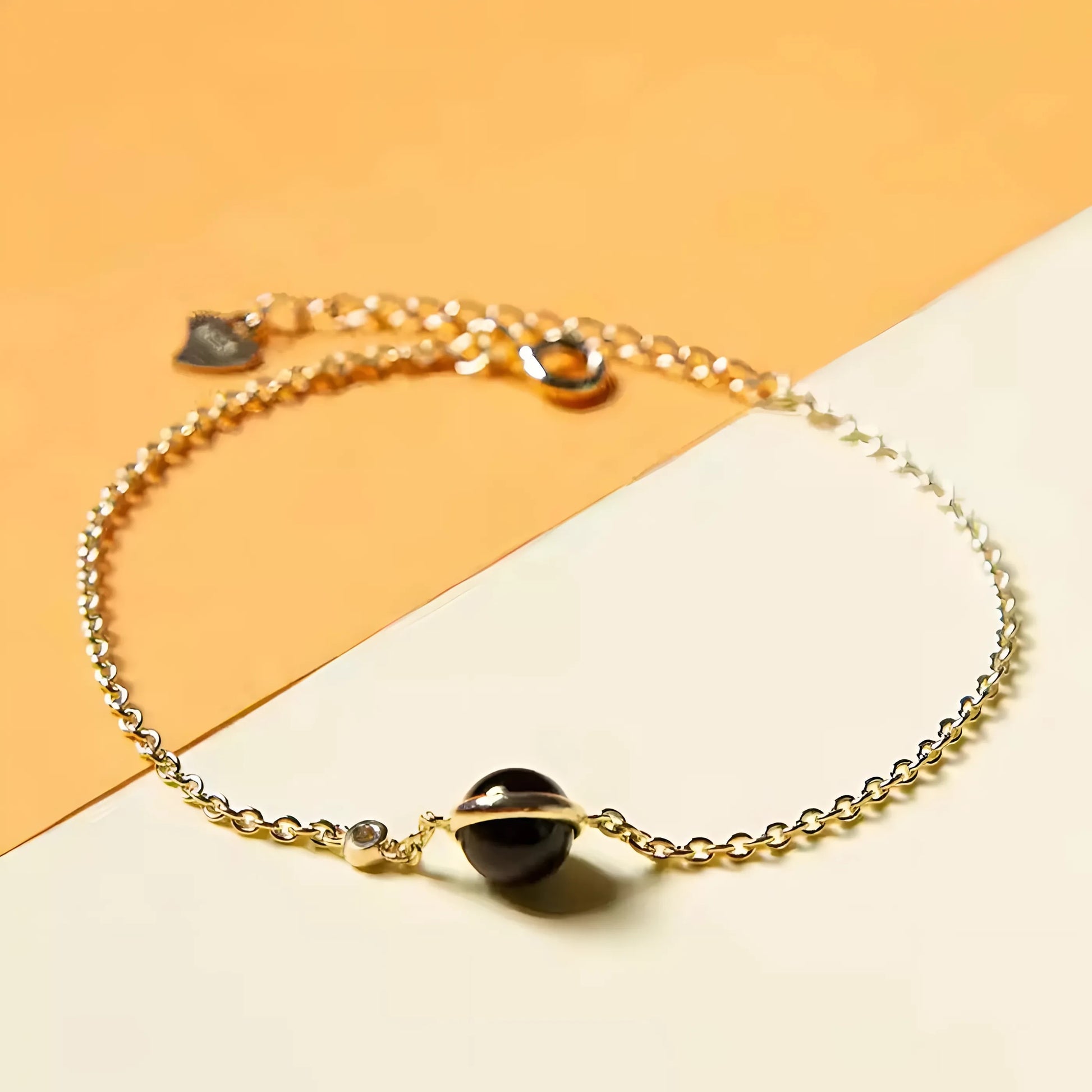 Model draagt een verfijnde vergulde armband met een zwarte agaat als middelpunt, die klassieke gratie belichaamt