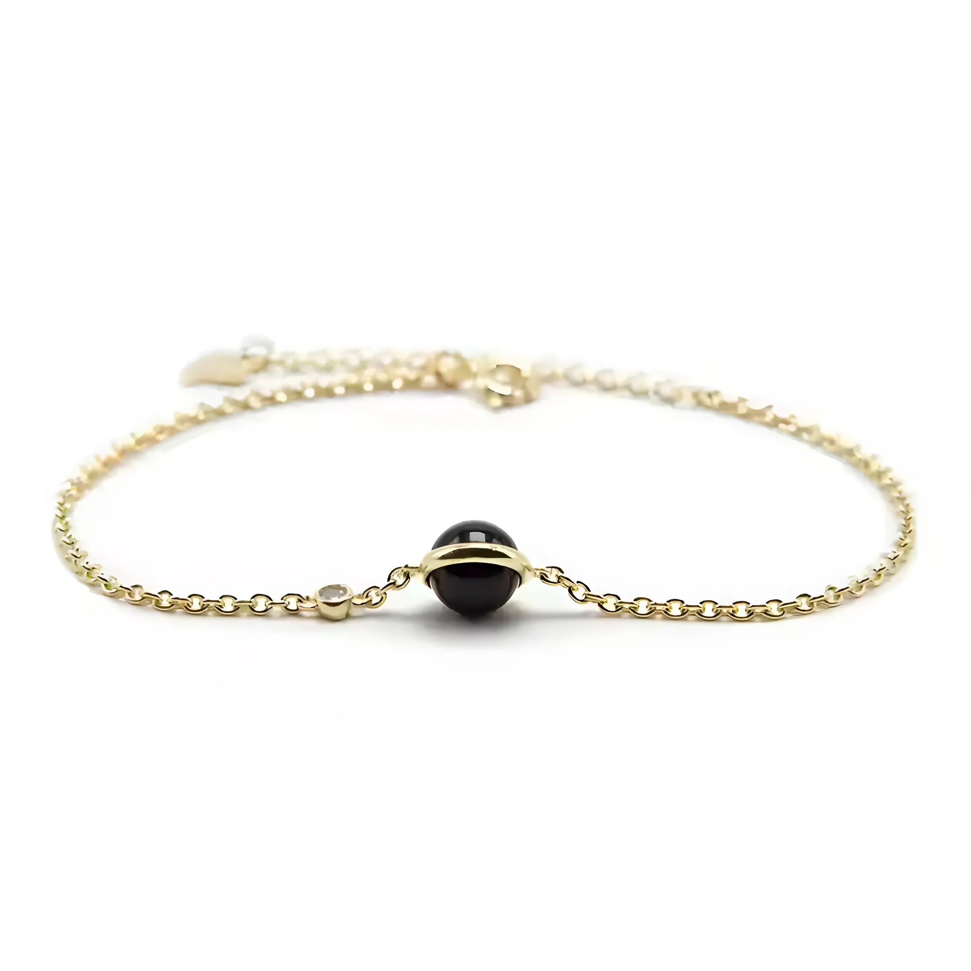 Gedetailleerd zicht op de zwarte agaatsteen van een vergulde armband, die de essentie van verfijnde eenvoud vastlegt