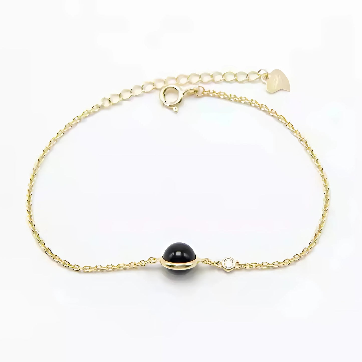 Close-up van een 14-karaats vergulde armband met een centrale zwarte agaatsteen, die tijdloze verfijning uitstraalt