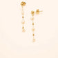 Gouden studs met delicate kettingen en witte parels, die een vleugje tijdloze verfijning bieden.
