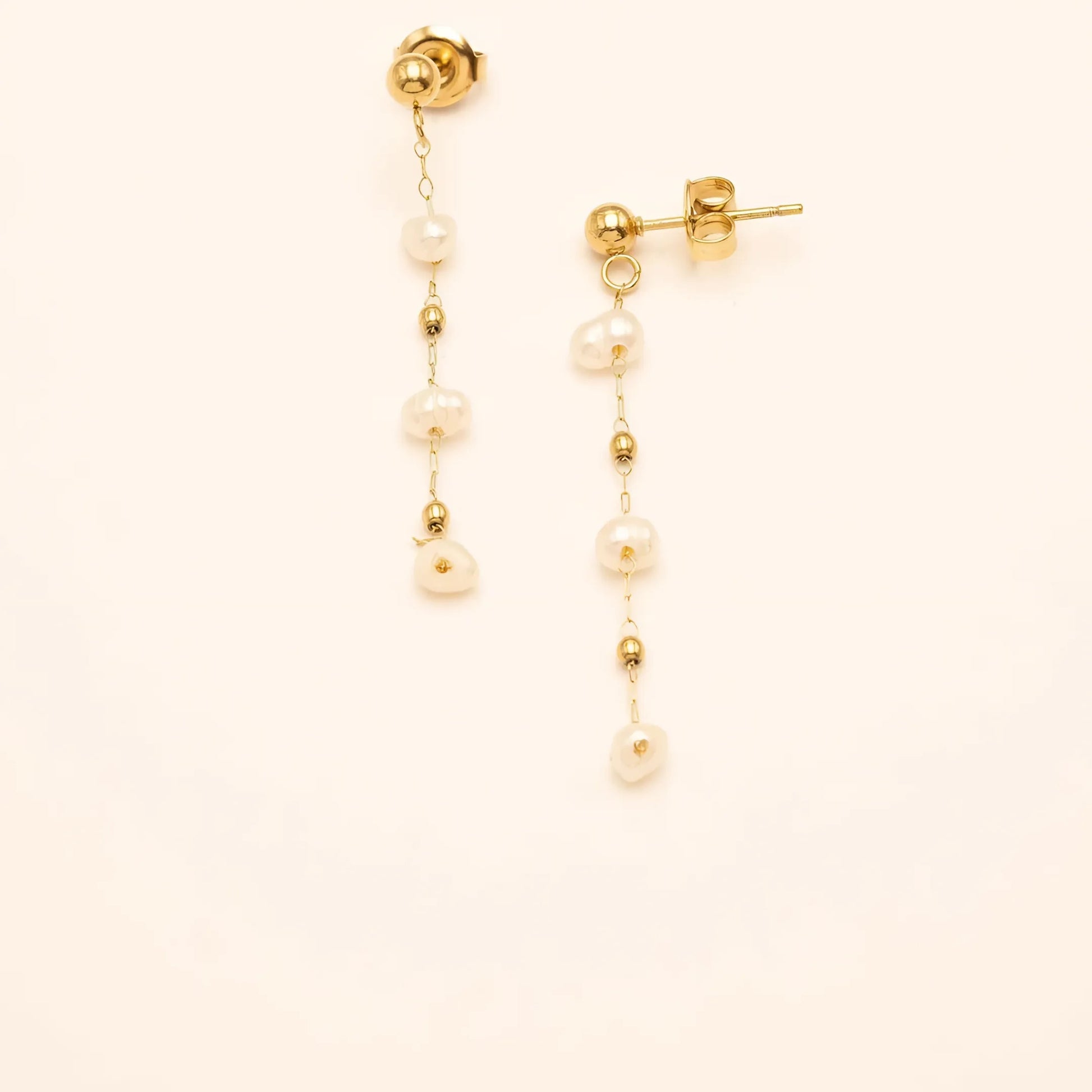 Gouden studs met delicate kettingen en witte parels, die een vleugje tijdloze verfijning bieden.
