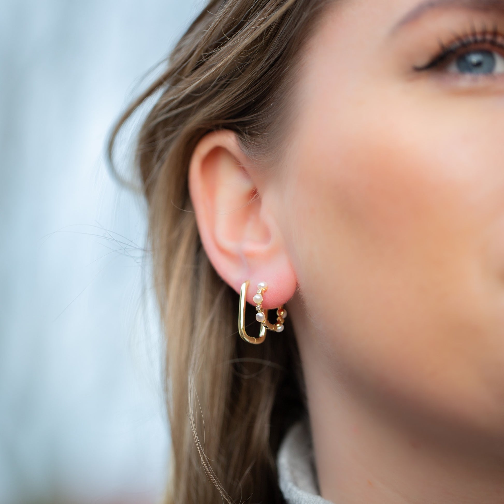 Gouden hoops versierd met glanzende witte parels, die tijdloze gratie uitstralen.
