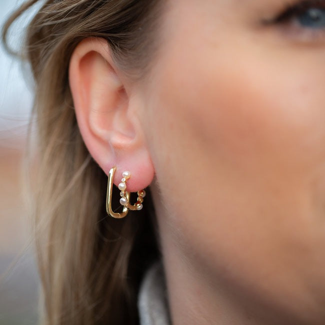Vergulde hoops met delicate witte parels, die de essentie van verfijnde schoonheid vastleggen.
