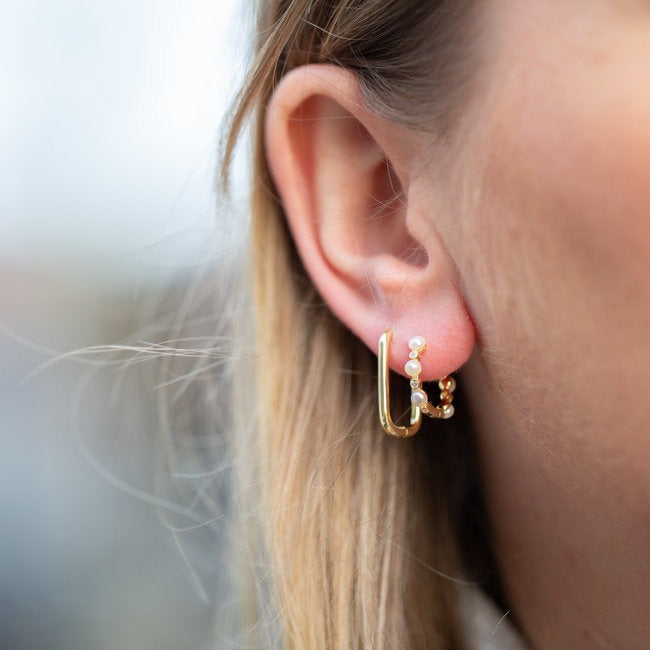 Elegante gouden hoops versierd met ongerepte witte parels, perfect voor elke gelegenheid.