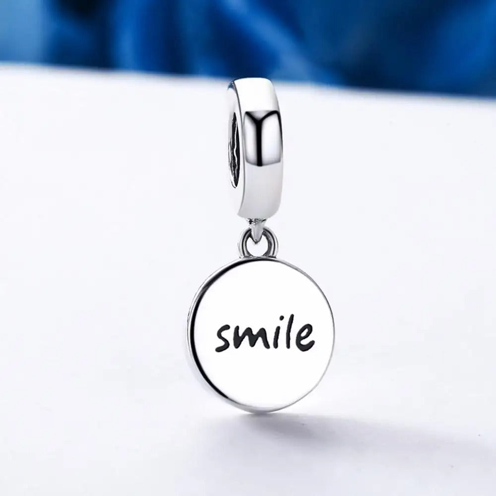 Een klein gouden bedeltje, waarvan het smiley-gezichtje glanst en geluk belooft aan iedereen die zijn stralende licht draagt