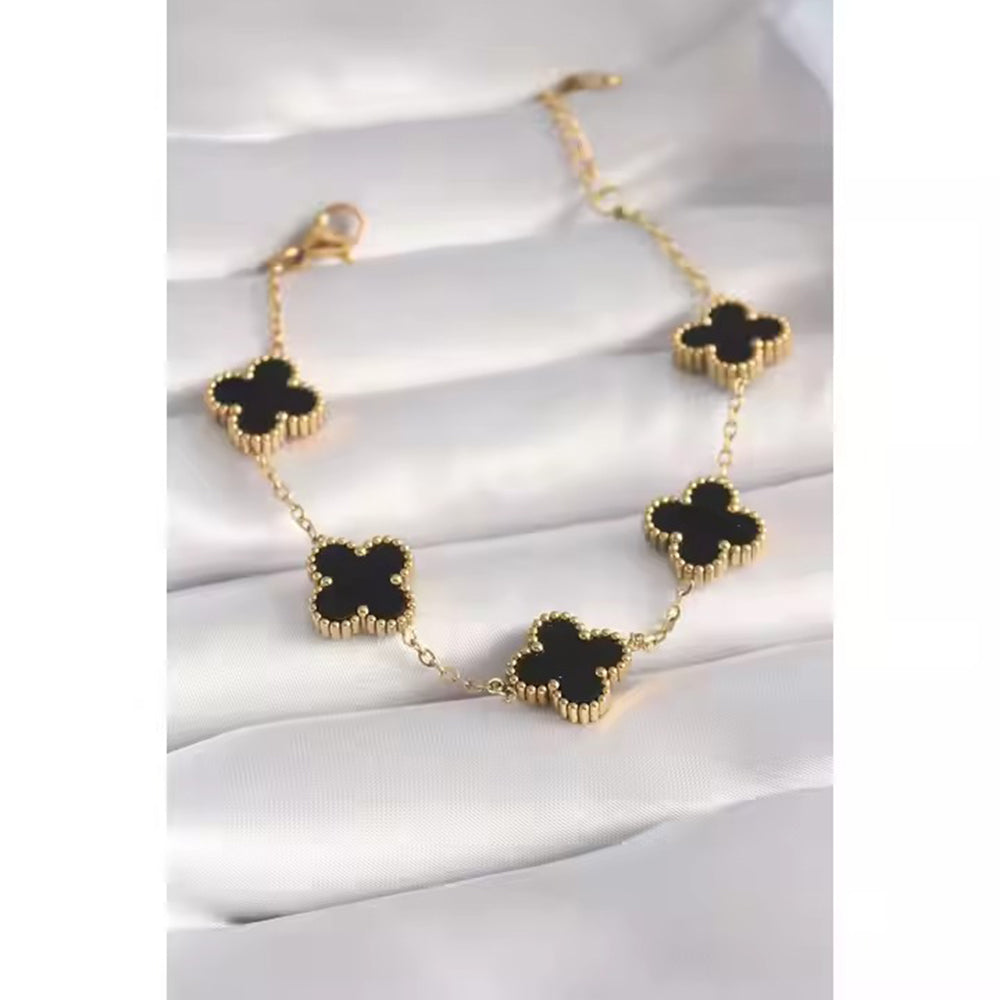 Close-up van een gouden armband met levendige klaverbedels, die een spectrum van geluk vastleggen