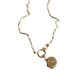Een delicate gouden ketting met een voorwaartse sluiting, versierd met een klein rond medaillon, die tijdloze elegantie belichaamt.
