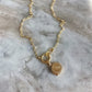 Elegante gouden ketting met een voorwaarts geplaatste sluiting, waaraan een verfijnd rond medaillon hangt, perfect voor lagen.