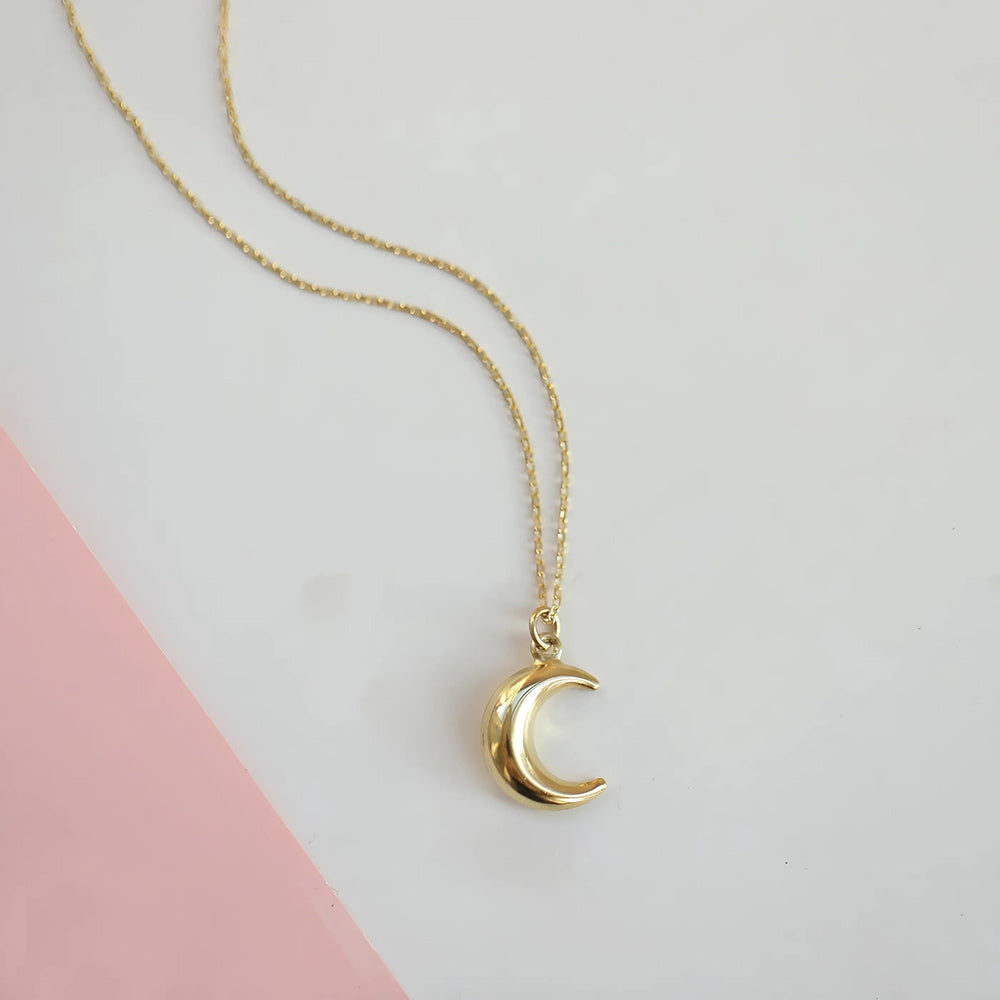 Vergulde ketting met een minimalistische maanhanger, die de rust van een sterrenavond oproept.