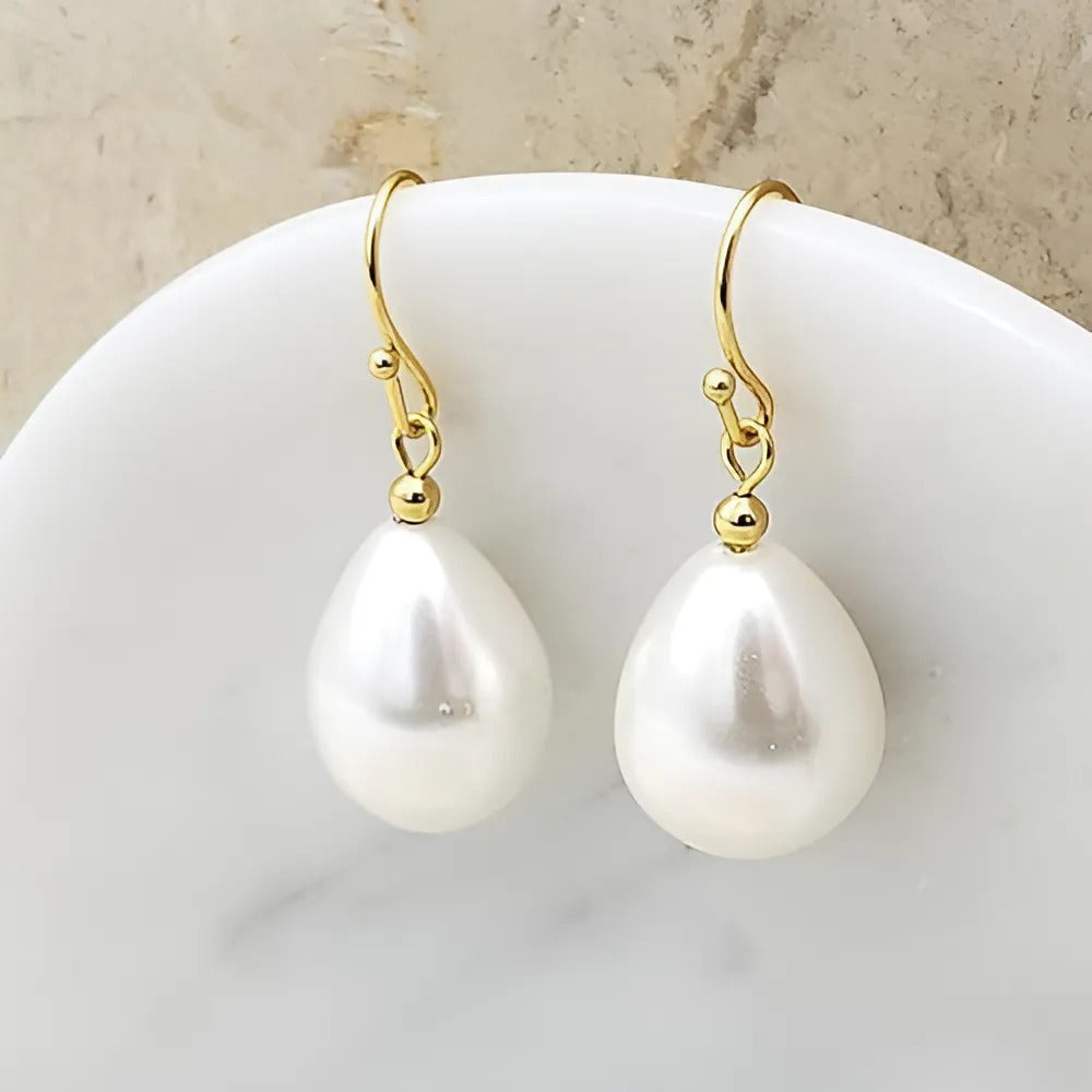 Gepolijste vergulde oorbellen met delicate witte parels, een harmonieuze mix van verfijning.
