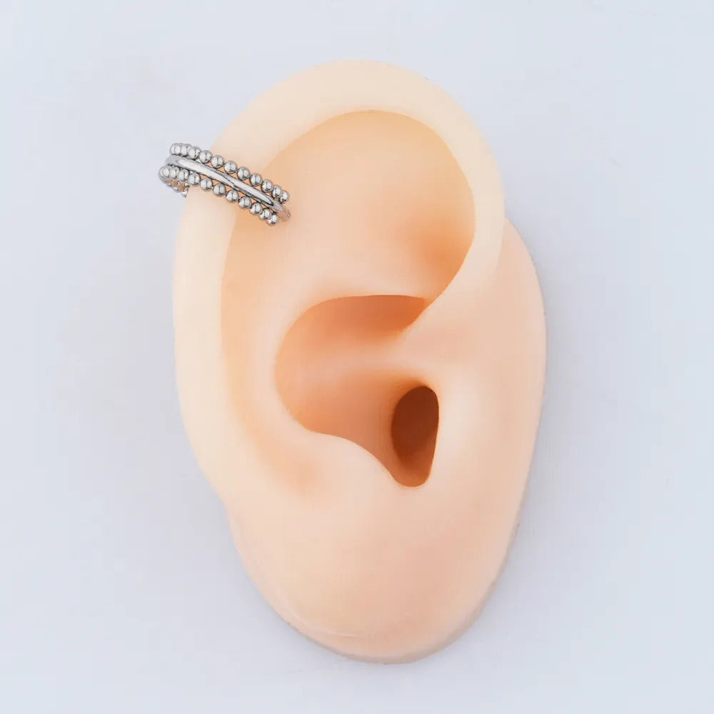 Een glinsterende helix-ring, waarvan de kralen-details doen denken aan oude tribale sieraden