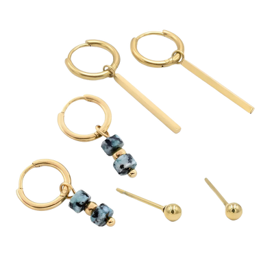 Drie paar goudkleurige oorbellen: hangende staafjes, hoops met blauwe kralen en eenvoudige studs, een harmonieuze mix van stijlen.